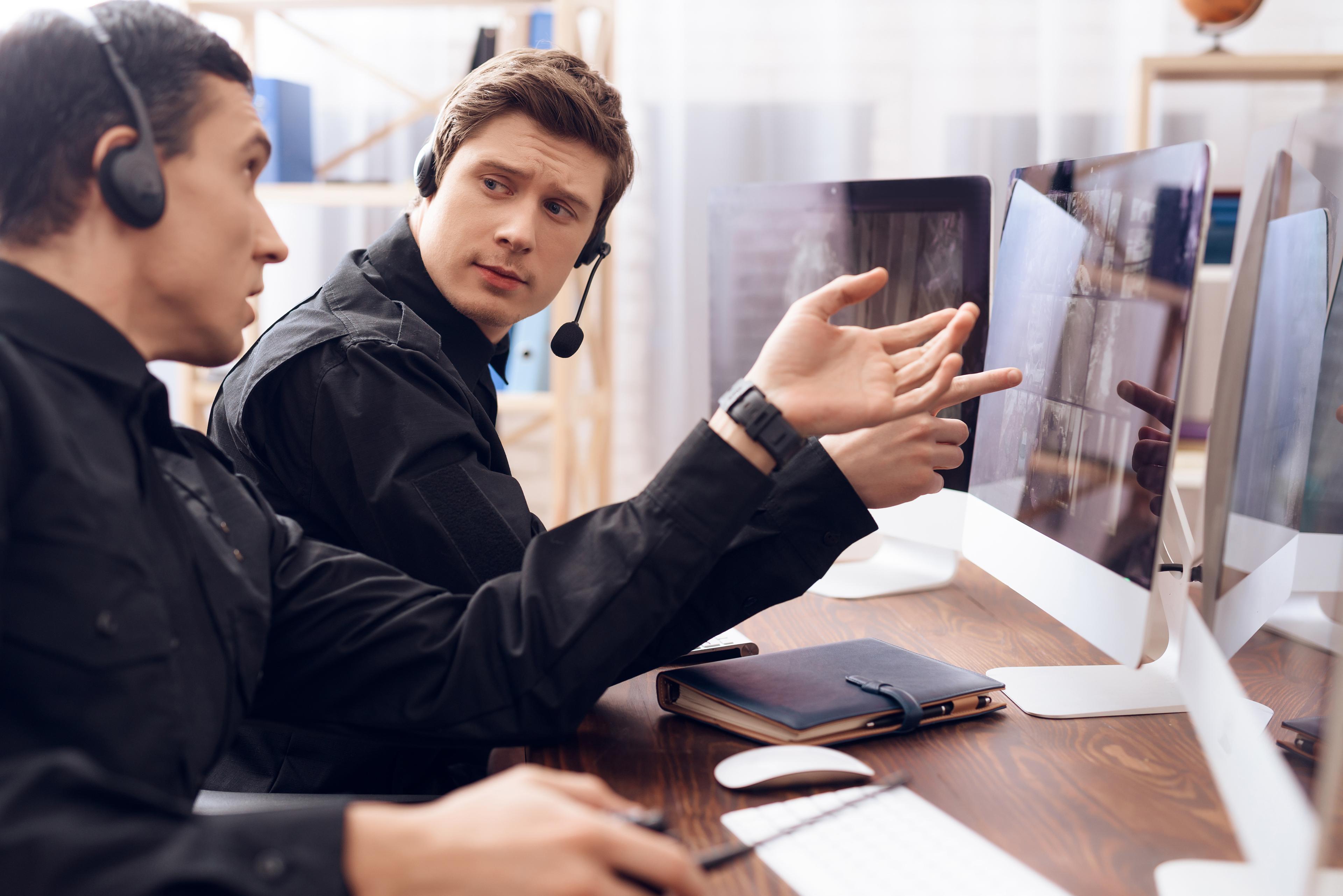 Security specialists with headsets reviewing monitoring data at workstations